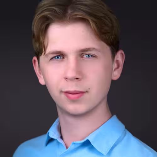 Fotograf headshot Leszno – biznesowy portret Jeremiego Rękosia, młodego mężczyzny o jasnej cerze i niebieskich oczach, w jasnoniebieskiej koszuli, na ciemnym tle.