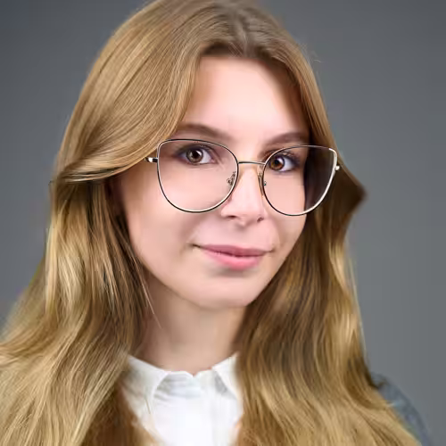 Fotograf headshot Leszno – biznesowy portret Zuzi Wojciechowskiej-Rękoś, kobiety o jasnych włosach w okularach, w jasnej koszuli, na neutralnym tle.